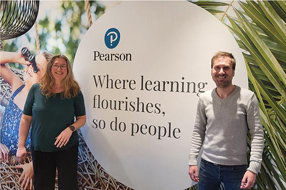 Foto: Eva Breedijk (l) en Martij Laman poseren voor een muur met daarop het logo van Pearson en een quote: Where learning flourishes, so do people