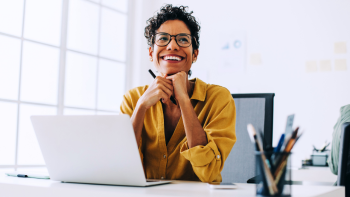 werknemer kijkt blij op vanachter de laptop