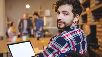 jonge man kijkend naar achter over zijn schouder en met voor hem een laptop